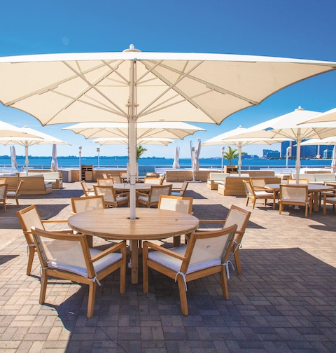 Tische mit Bahama-Jumbrella Sonnenschirmen auf Restaurantterrasse – erhältlich bei Seeckts